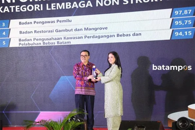 Komisioner Komisi Informasi (KI) Pusat Bidang Penelitian dan Dokumentasi, Rospita Vici Paulyn (kanan) memberikan piala kepada Anggota Bidang Kebijakan Strategis BP Batam, Enoh Suharto Pranoto.
